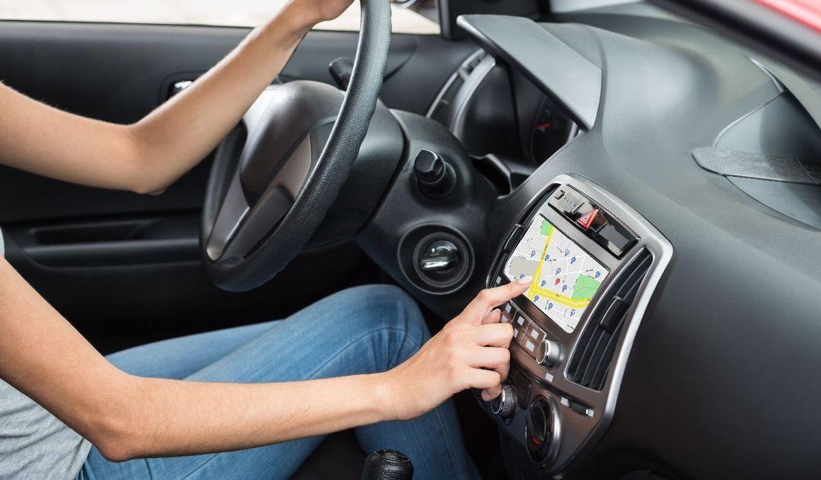 Brazos de mujer señalando el GPS mientras conduce el auto.jpg