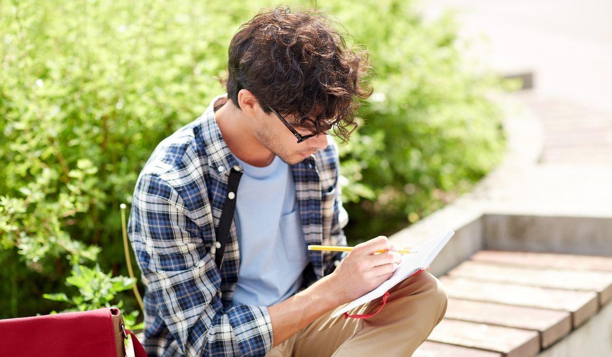 Un hombre escribe en un cuaderno al aire libre