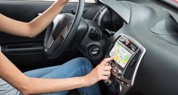 Brazos de mujer señalando el GPS mientras conduce el auto.jpg