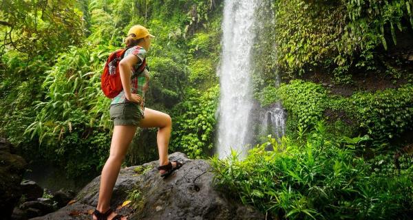 Mujer mira una catarata pequeña en el medio de la selva